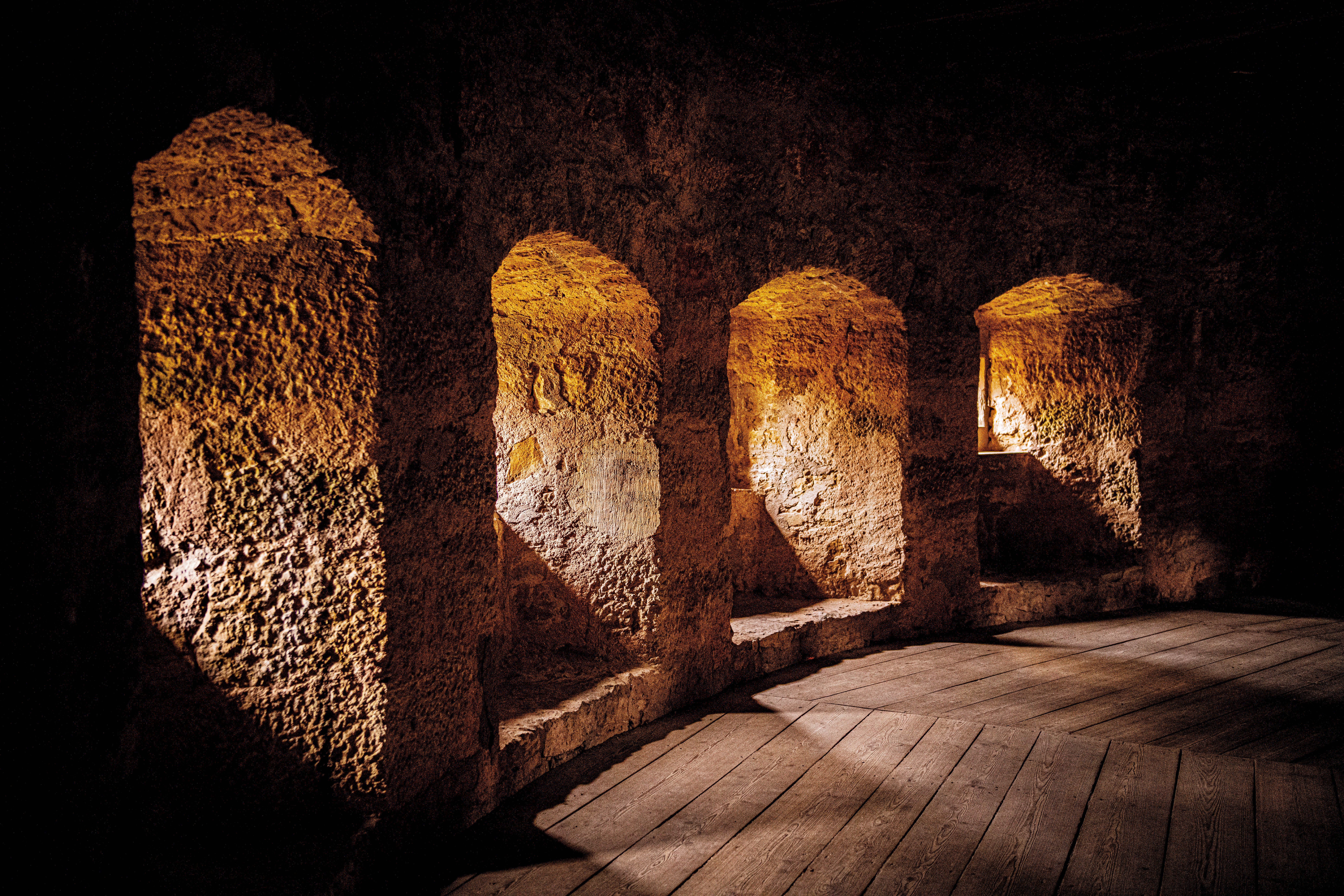 Three arches constructed from stone illuminated by light streaming through them